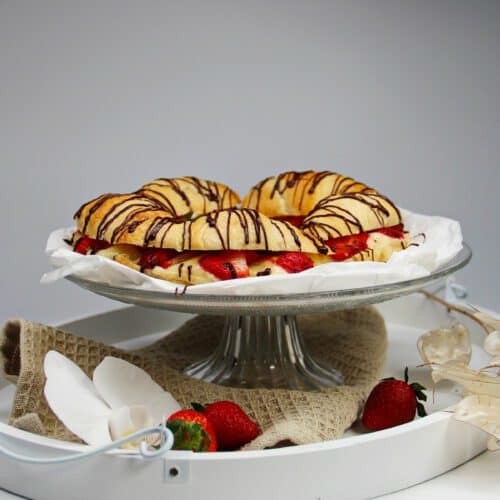 Croissant Torte mit Erdbeeren und Pudding auf einem Glasteller