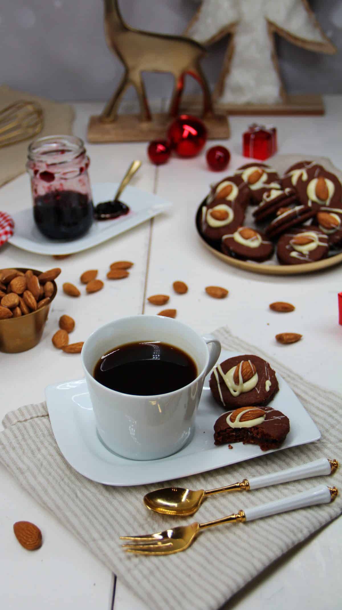 Schoko-Plätzchen mit Mandeln auf einem weißen Teller neben einem Kaffee