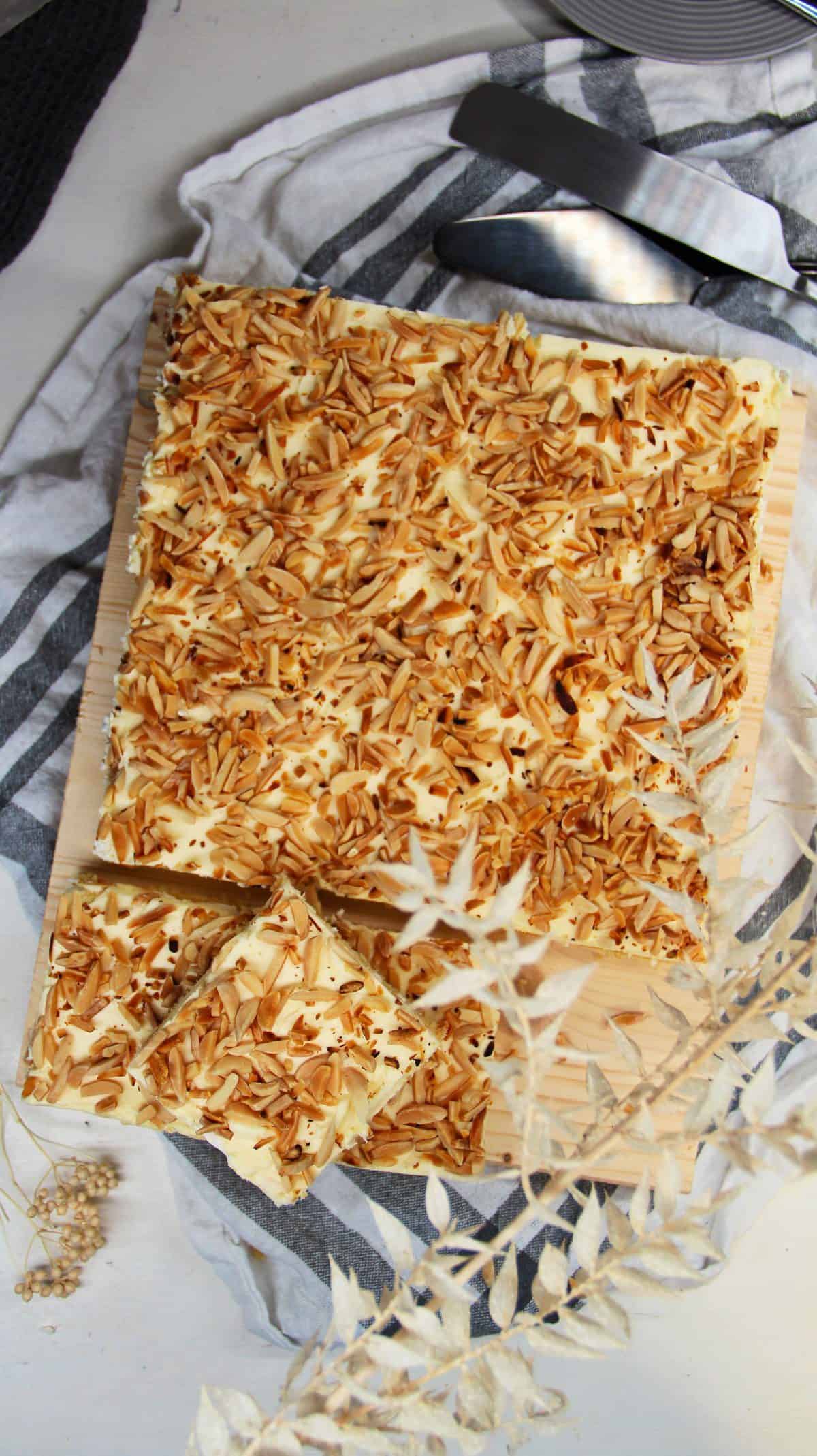 Baiserkuchen mit Mandeln, Blechkuchen auf einer Holzplatte serviert