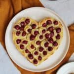 Blätterteigherz mit Kirschen und Pudding auf einem weißen Teller