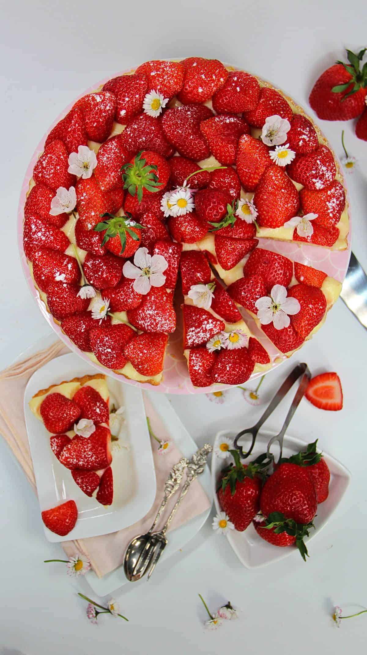 Erdbeerkuchen mit Puddingcreme mit Erdbeeren und Blüten dekoriert