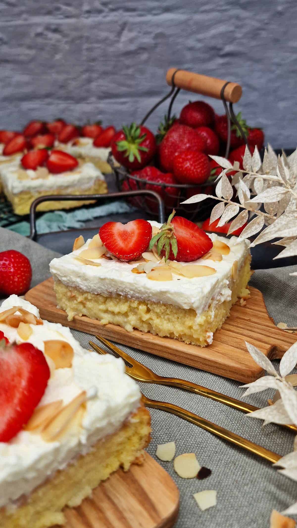 Tres leches Kuchen, Kuchenstück mit frischer Erdbeere und gehobelten Mandeln auf einem Holzbrettchen