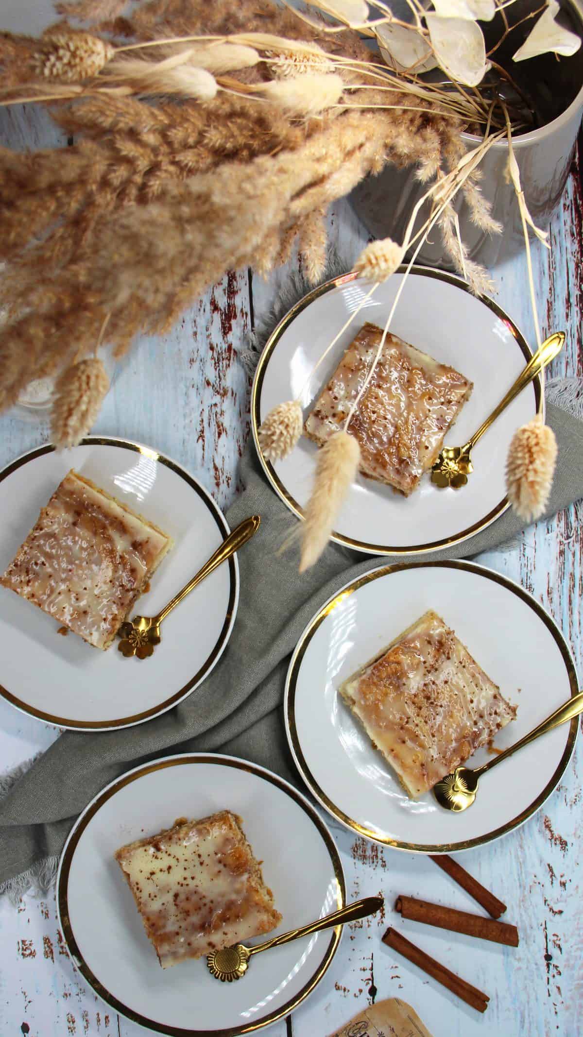 Zimtschneckenkuchen auf Tellern mit  Goldrand sowie goldenen Löffeln