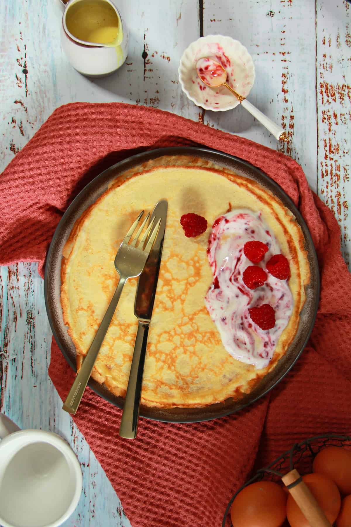 Quark-Pfannkuchen auf einem Teller mit einem großen Klecks Joghurt und Himbeeren