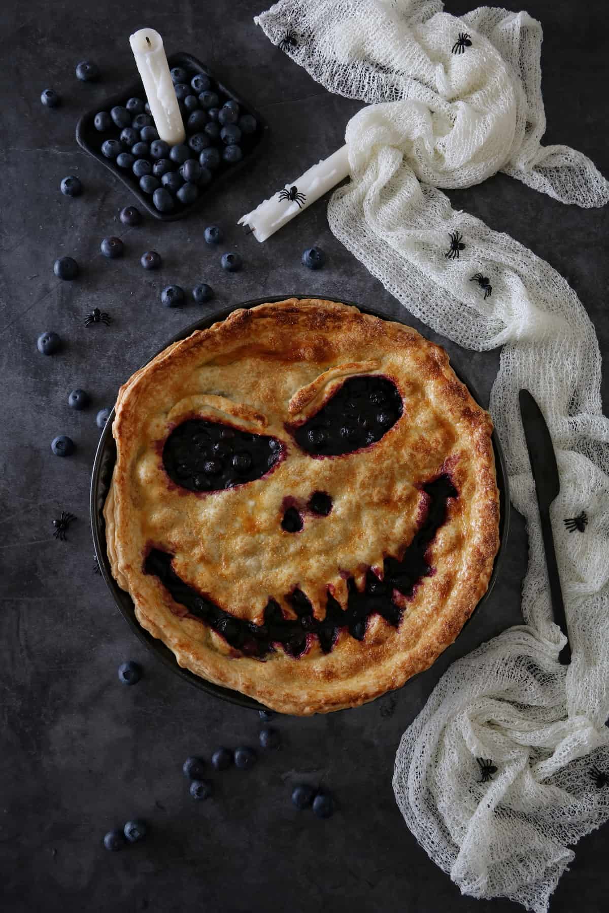 Blaubeer-Tarte zu Halloween mit Fratze auf einem dunklen Hintergrund