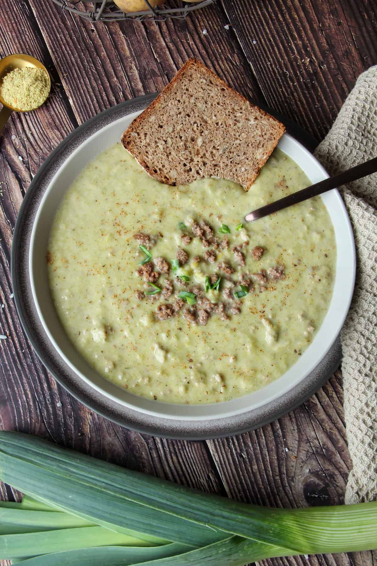 Käse-Lauch-Suppe mit Hackfleisch und Kartoffeln aus dem Thermomix® in einem Teller mit einer Scheibe Brot