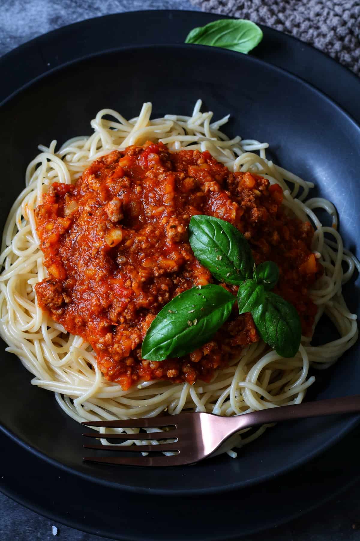 Spaghetti Bolognese aus dem Thermomix® in einem tiefen Teller, mit Basilikum garniert. Von oben fotografiert.