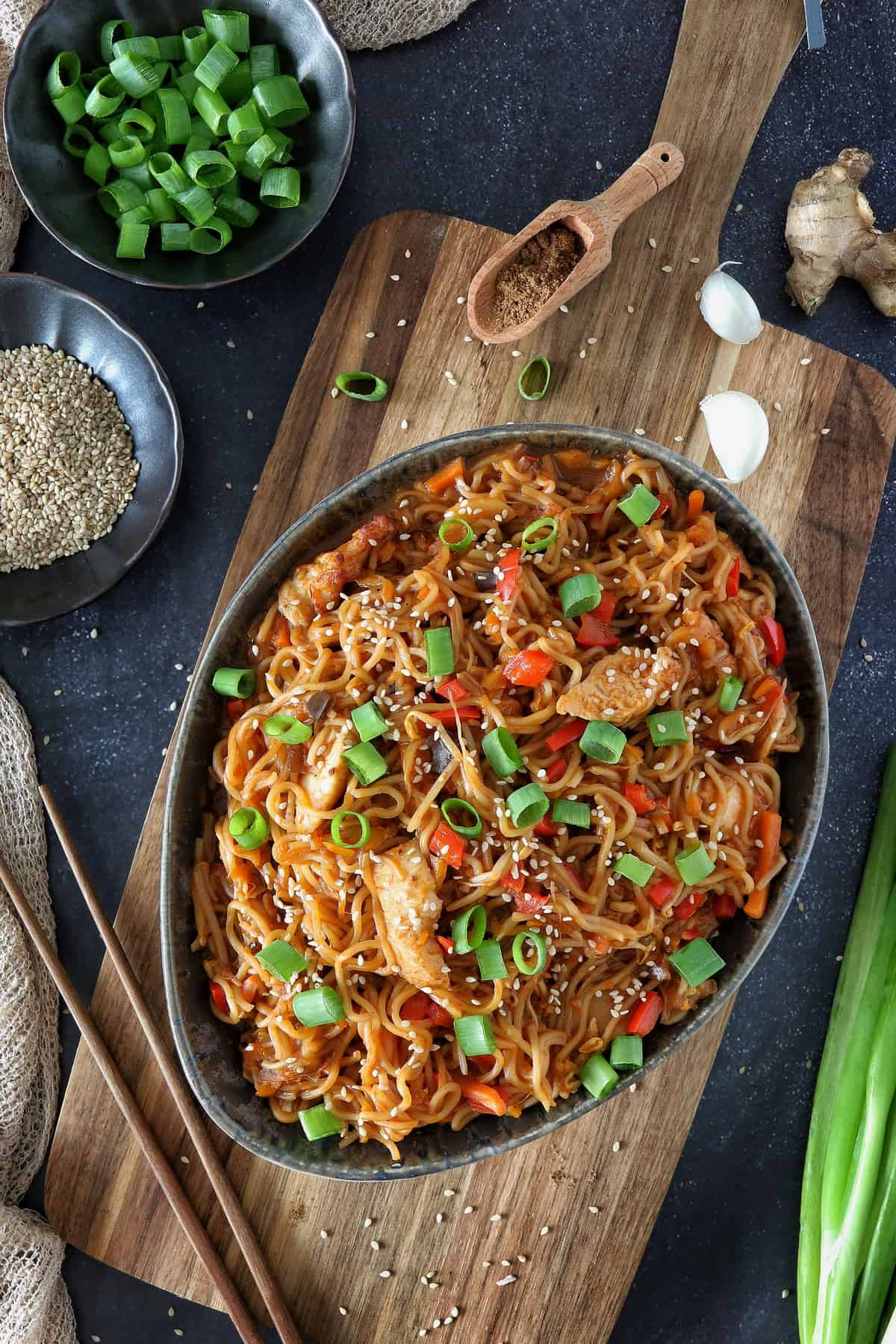 All-in-One-Gericht: Chinesische Nudeln mit Gemüse und Hähnchen aus dem Thermomix® in einer schwarzen Schale, mit Schnittlauch und Sesamsamen garniert