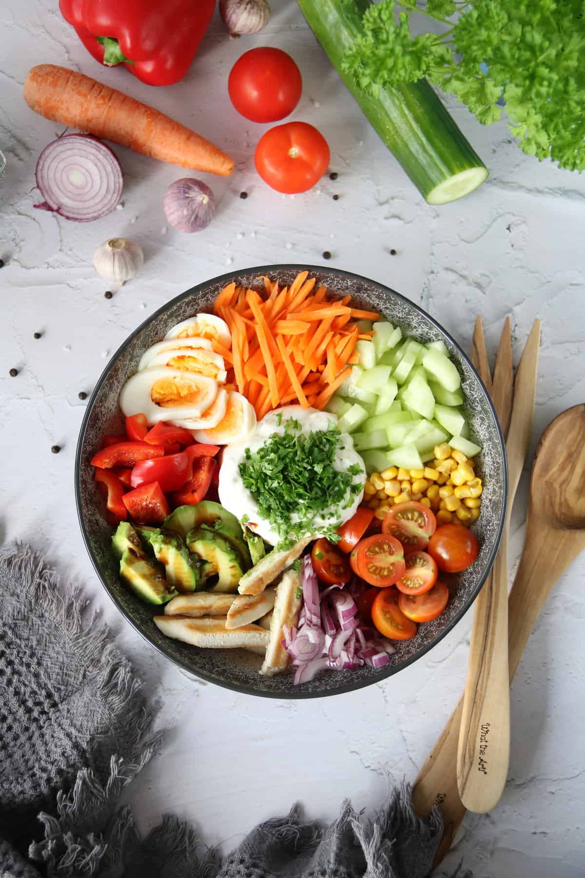 Bunte Salat Bowl mit Avocado, Hähnchen und Knoblauchdressing in einer Schüssel angerichtet. Von oben fotografiert.