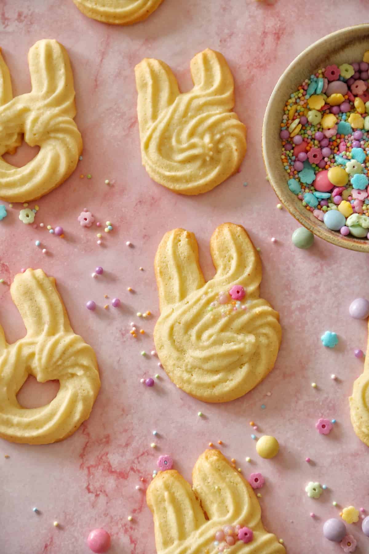 Spritzgebäck für Ostern abgewandelt: Ein Hasenkopf mit langen Ohren wurde auf dressiert. Die gebackenen Kekse liegen auf einem rosa Untergrund.