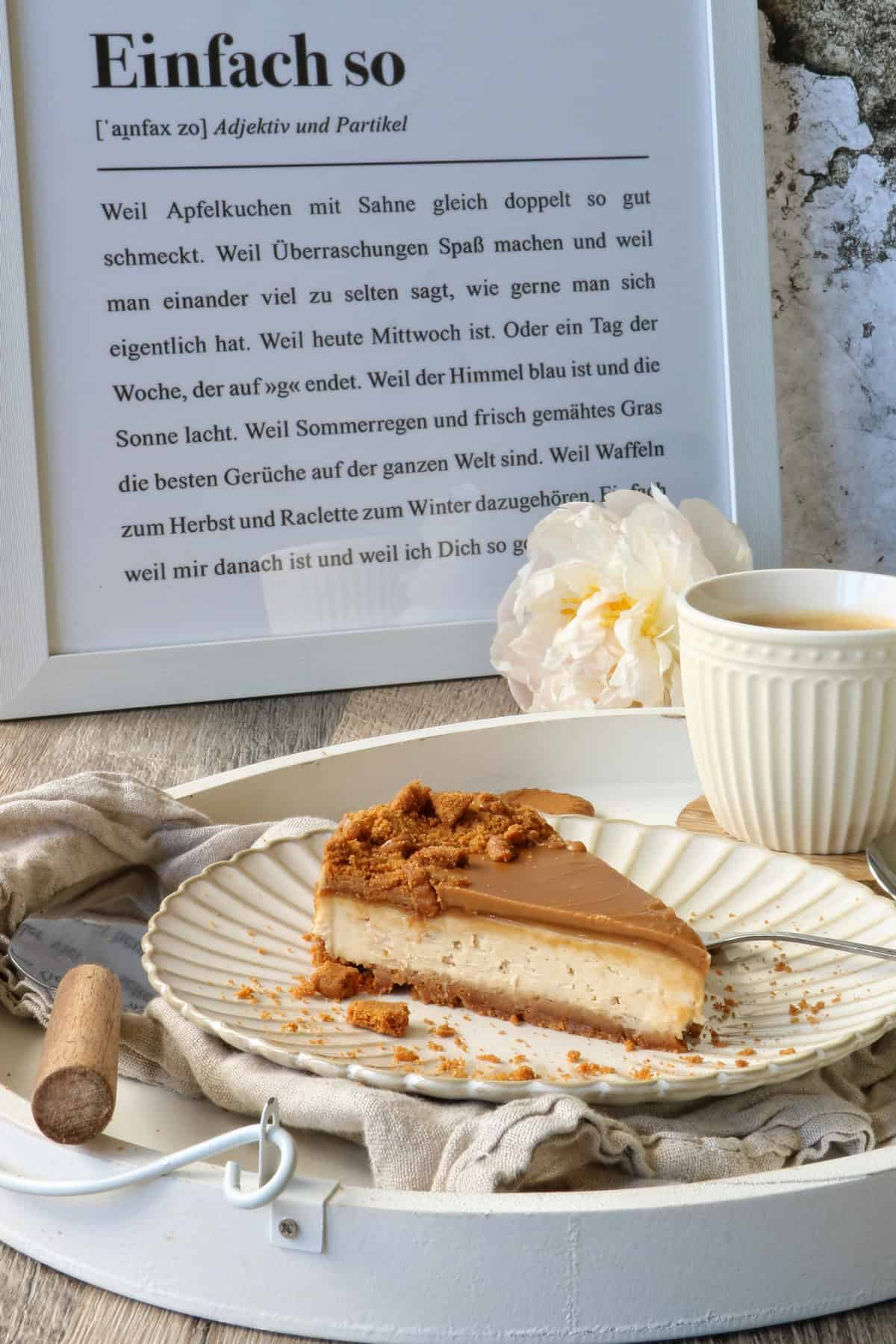 Tablett mit Lotus Biscoff Cheesecake und einer Kaffeetasse vor einem Poster 