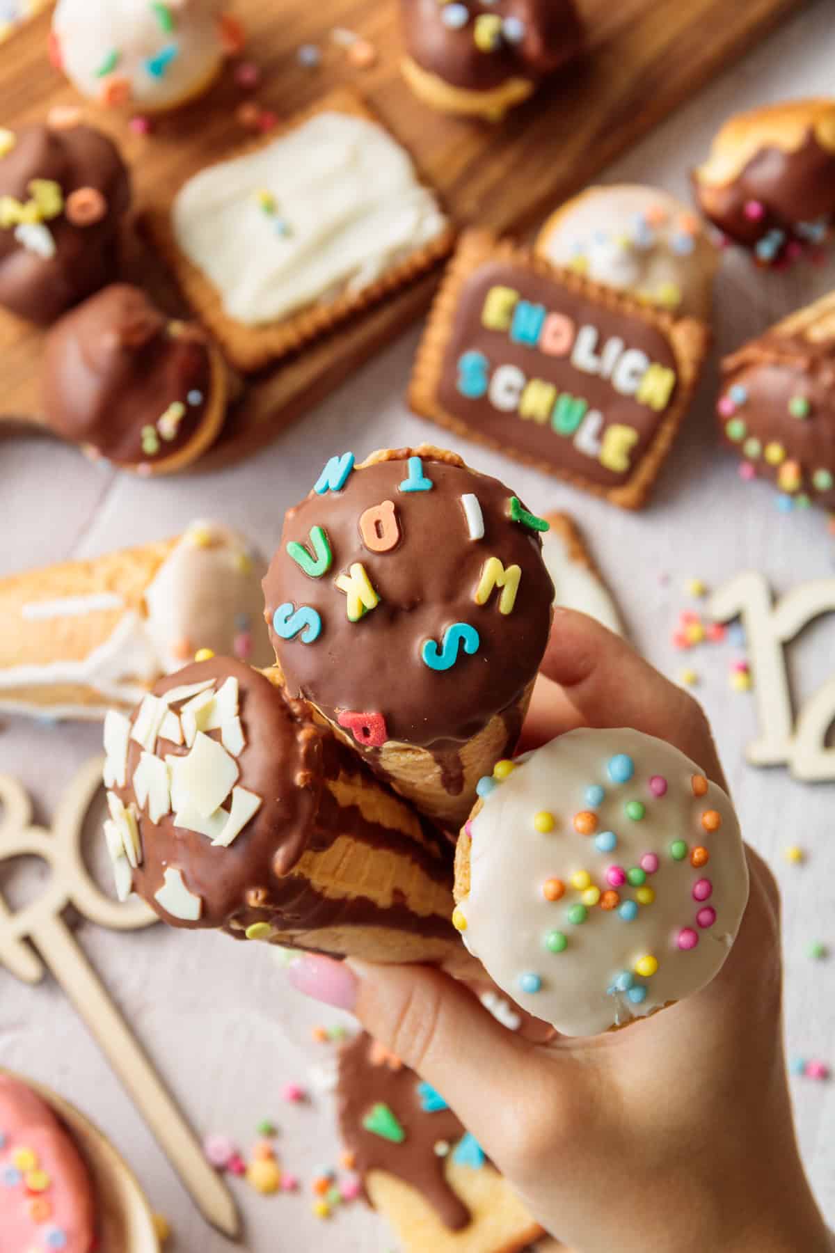 Eine Hand hält 3 Schultüten-Eiswaffeln, die hübsch dekoriert sind.