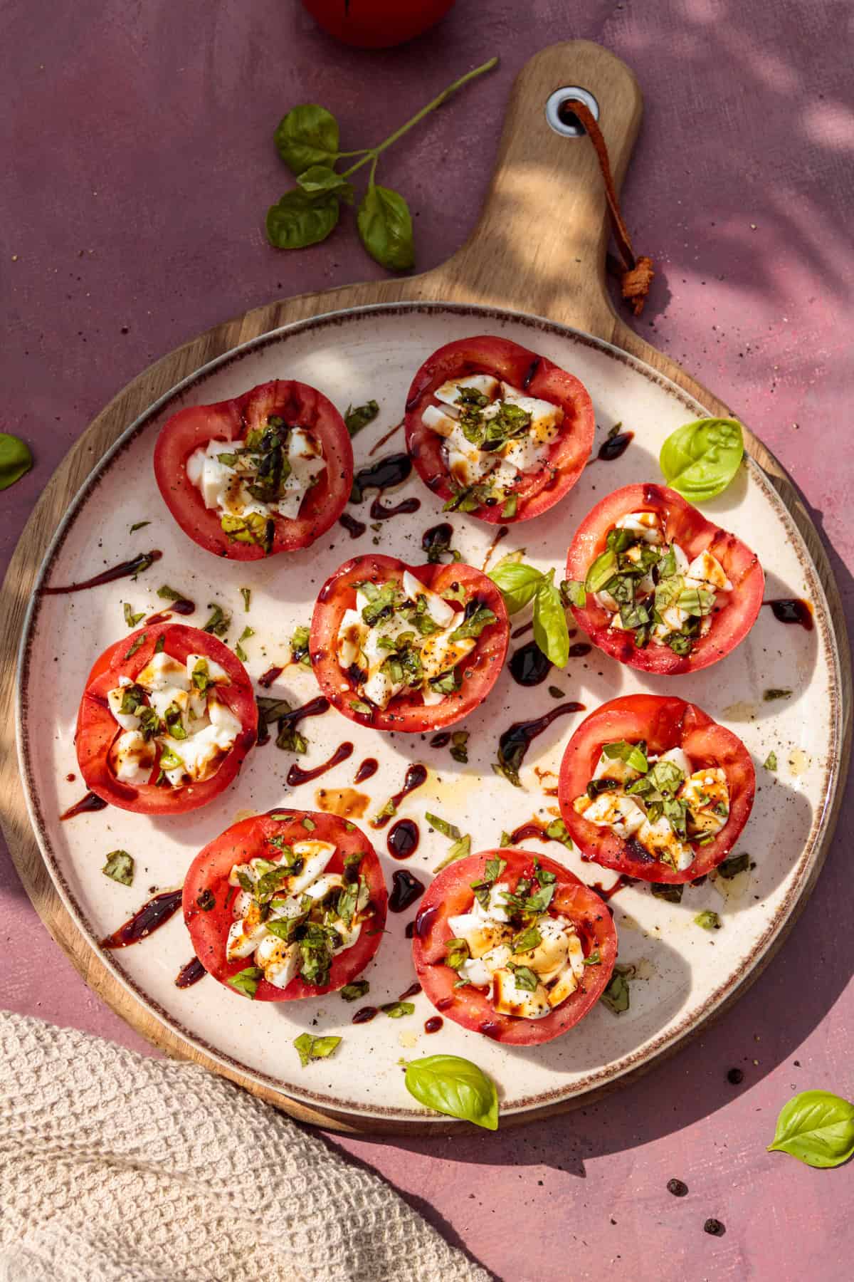 Gefüllte Caprese-Tomaten auf einem hellen Teller im Sonnenlicht fotografiert.