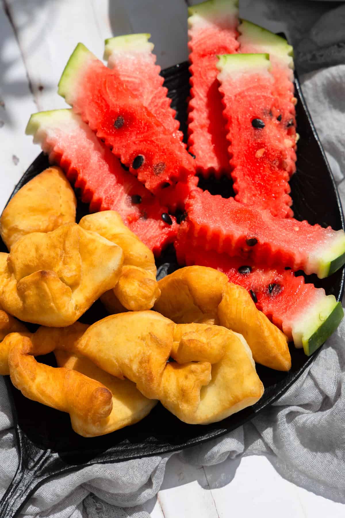 Rollkuchen-ein Gebäck aus dem plattdeutschen- mit Wassermelone auf einem schwarzen Teller.