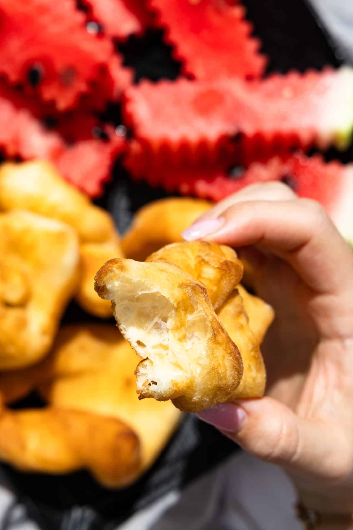 Rollkuchen (auch Krebli oder Faworki genannt), angebissen, in der Hand gehalten. 