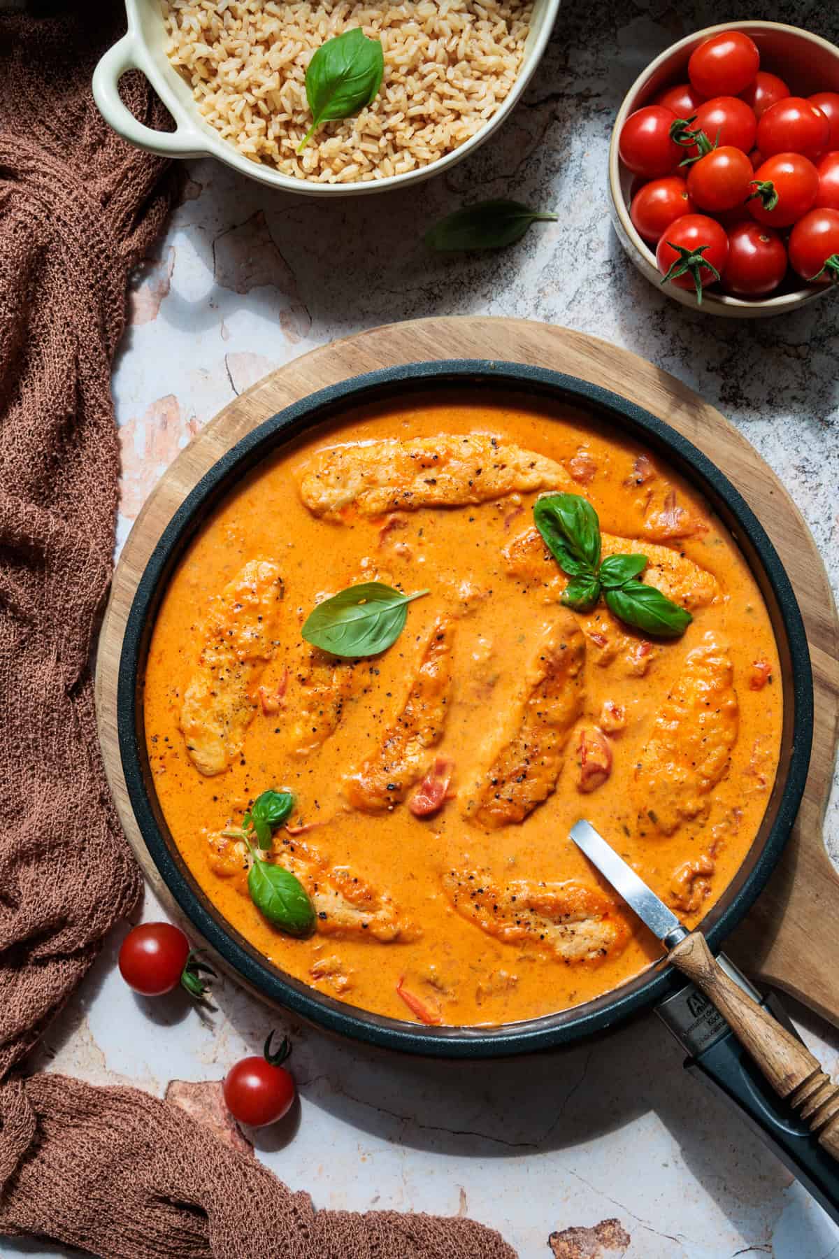 Hähnchenfilet in Frischkäse-Parmesan-Soße in einer Pfanne angerichtet, mit frischem Basilikum garniert