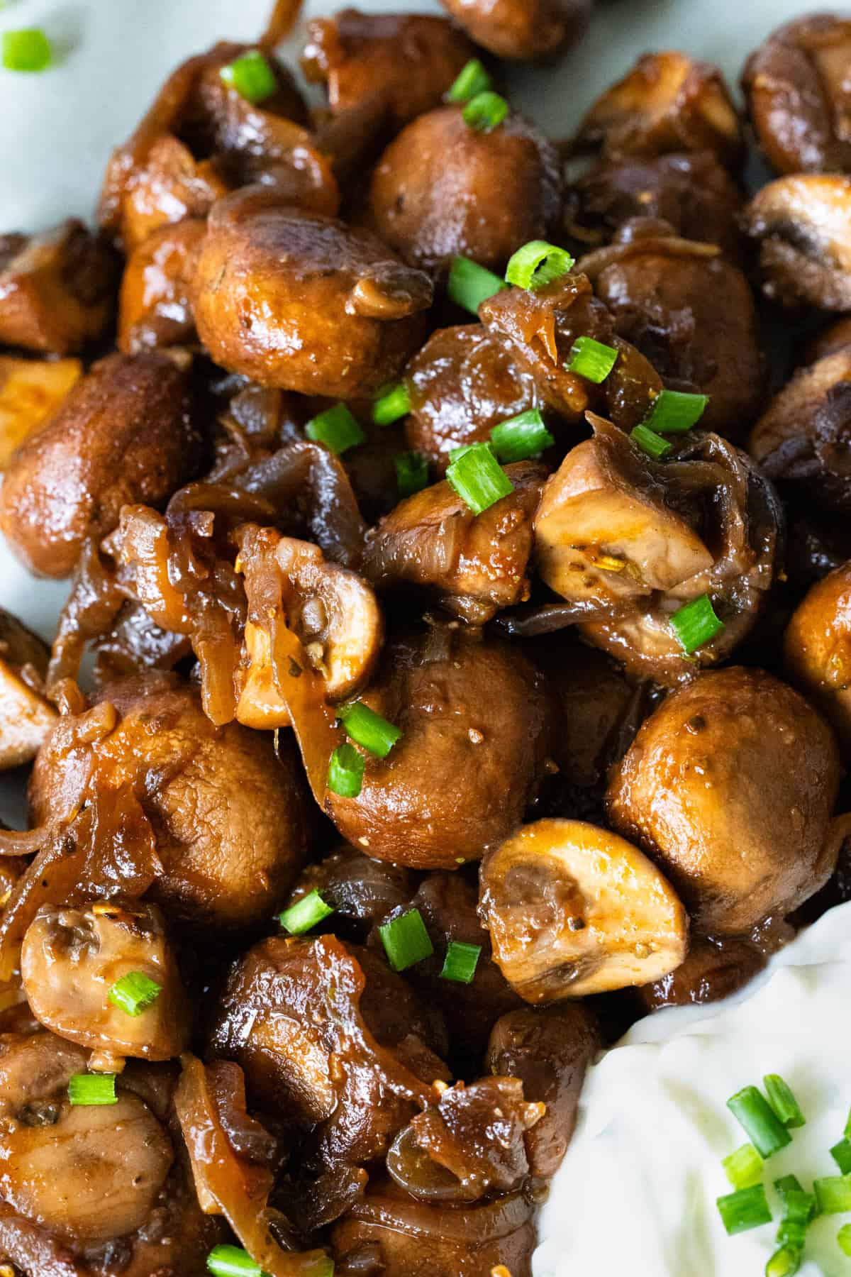 Champignons in Knoblauchsoße mit frischem Schnittlauch garniert, als Nahaufnahme.