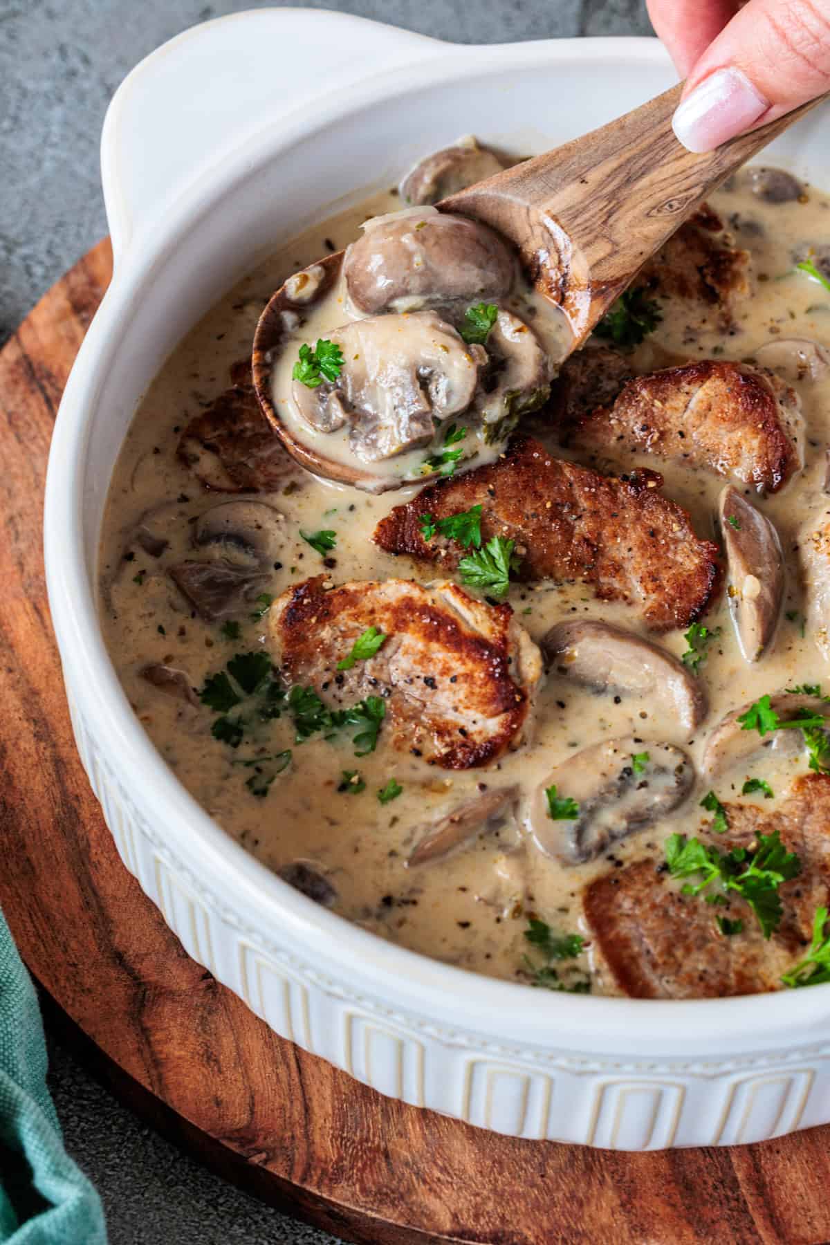 Schweinefilet in Champignon-Rahmsoße in einer Schüssel, die auf einem Holzbrett steht.