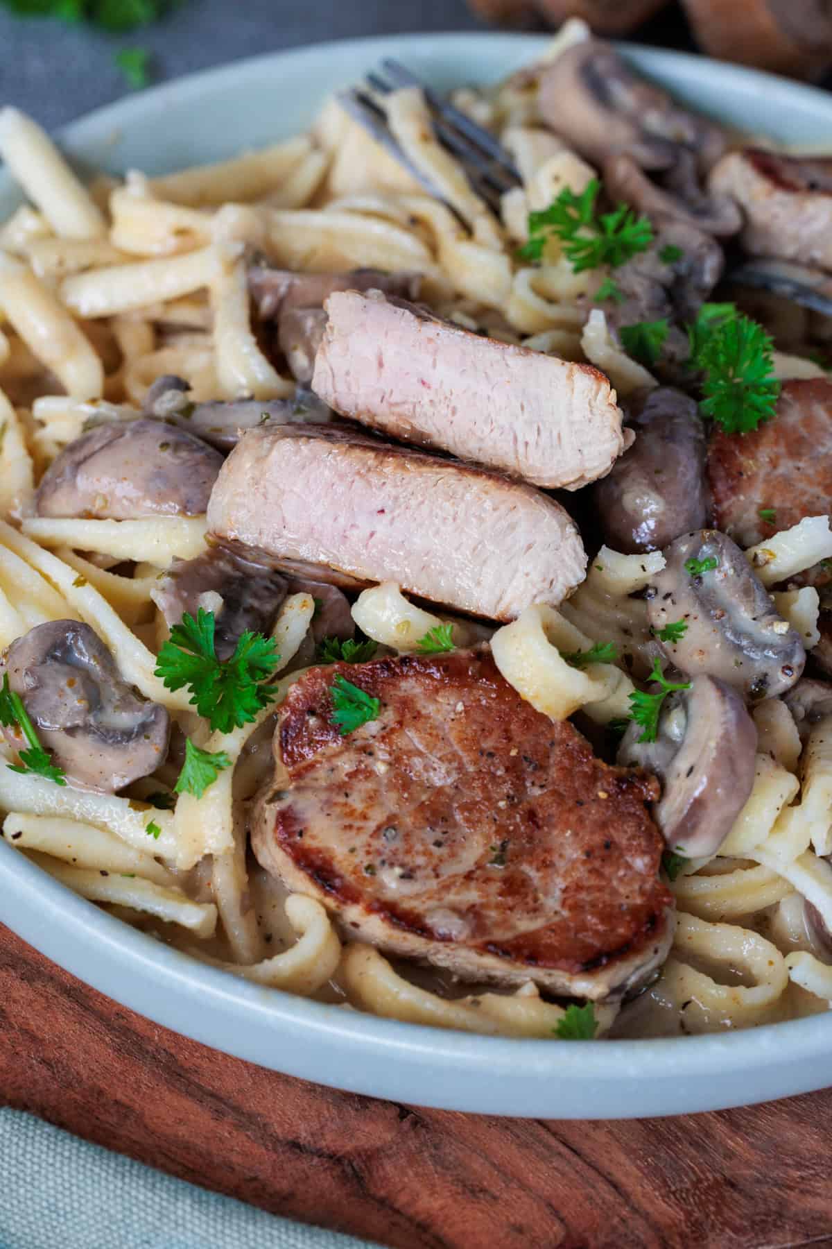 Schweinefilet in Champignon-Rahmsoße, auf einem Teller mit Spätzle. Ein Filetstück ist angeschnitten auf den Spätzle.