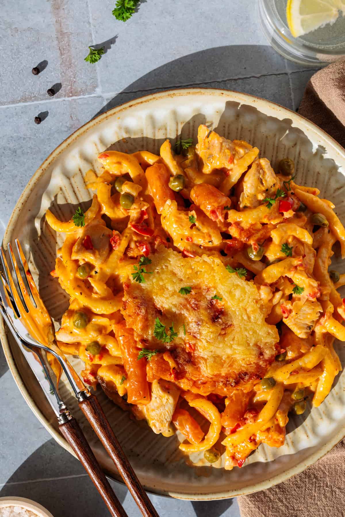 Spätzle-Auflauf mit Hähnchen, Gemüse und Käse überbacken auf einem Teller von oben fotografiert und mit Holzbesteck auf dem Teller.