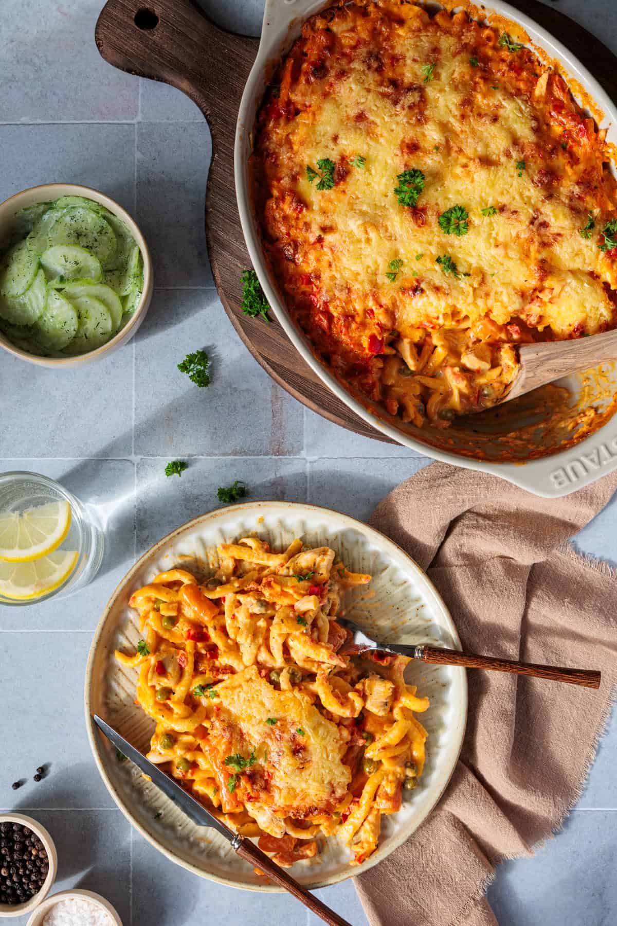 Spätzle-Auflauf aus dem Thermomix®, auf einem grauen Hintergrund. Sowohl die Auflaufform ist zu sehen, als auch eine Portion, die auf einem Teller angerichtet ist.