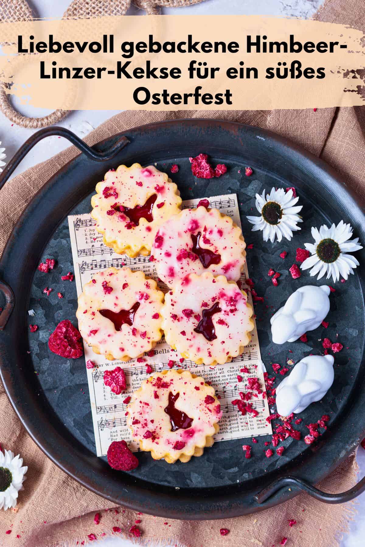 Pin zu Pinterest: Liebevoll gebackene Himbeer-Linzer-Kekse für ein süßes Osterfest: Himbeer-Linzer-Kekse auf einem rustikalen Tablett. Die goldbraunen Kekse sind mit einer zarten weißen Glasur überzogen und mit roten Himbeerstückchen dekoriert. Zwischen den Keksen liegen weiße Blüten und kleine Hasenfiguren.