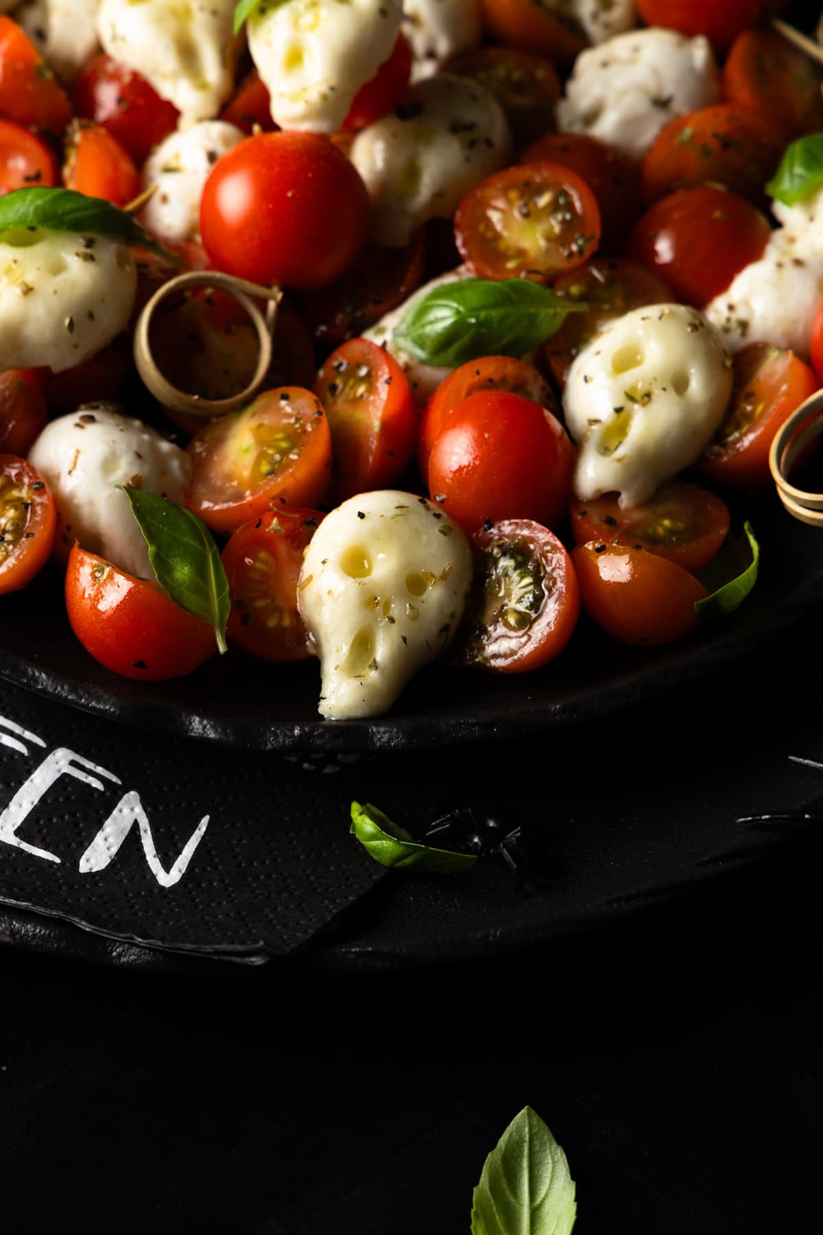 Nahaufnahme eines Caprese-Salats mit Totenkopf-Mozzarella und Kirschtomaten. Leckeres und gruseliges Halloween-Rezept für die Party.