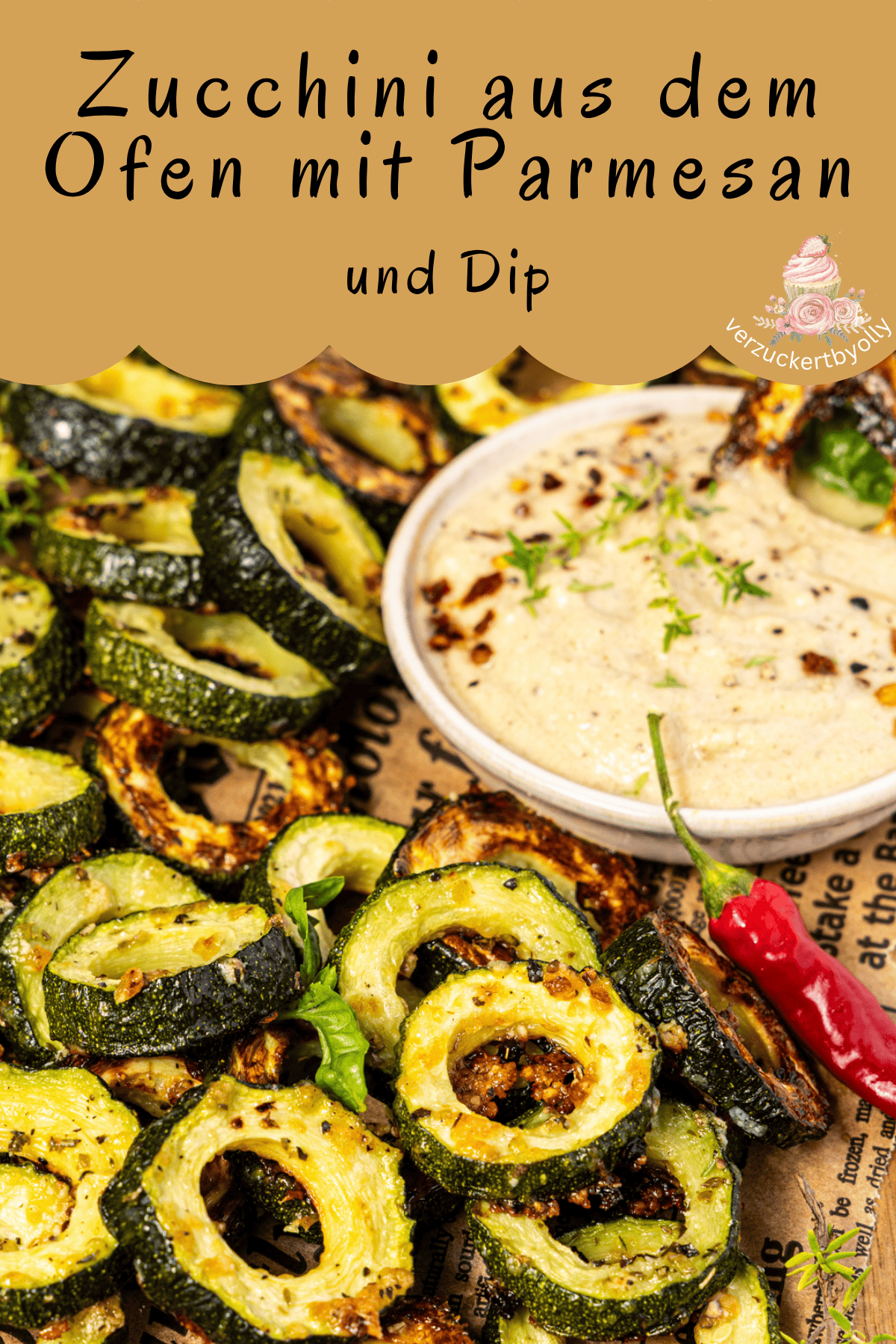 Ein Pin-Bild mit dem Titel "Zucchini aus dem Ofen mit Parmesan und Dip". Das Bild zeigt gebratene, ringförmige Zucchinischeiben mit Parmesan und einen cremigen Dip. Das Gericht ist auf einem Schneidebrett angerichtet, das mit Zeitungspapier belegt ist. Es ist mit einer roten Chilischote und frischen Kräutern garniert. In der oberen rechten Ecke befindet sich ein Logo mit dem Text "verzuckertbyolly".