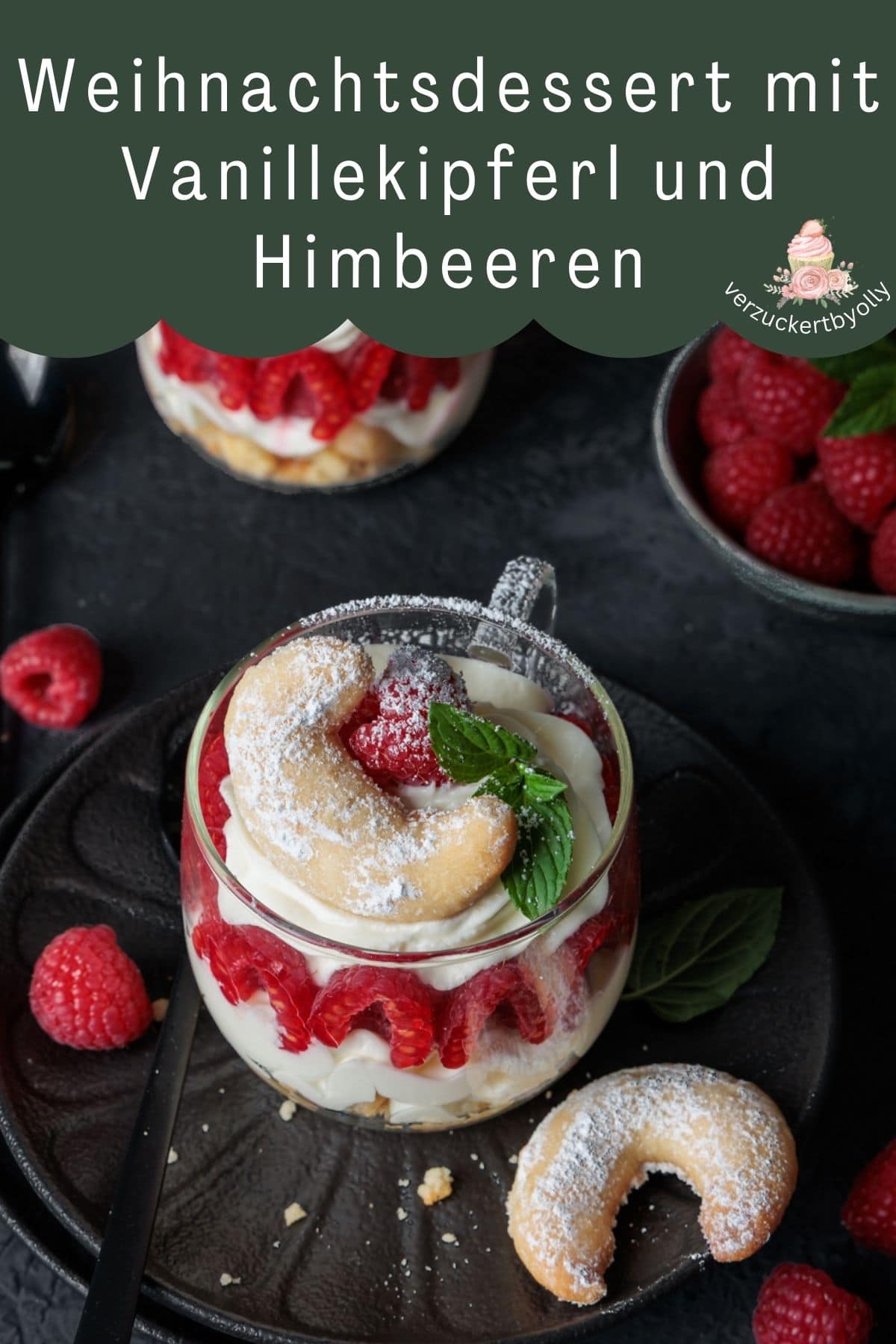 Eine visuell ansprechende Grafik für Pinterest, die ein Weihnachtsdessert mit Vanillekipferl und Himbeeren bewirbt. Im Vordergrund steht ein einzelnes Dessert im Glas auf einem dunklen Teller. Es besteht aus Schichten von weißer Creme und roten Himbeeren, gekrönt von einem mit Puderzucker bestreuten Vanillekipferl. Im Hintergrund sind zwei weitere, unscharfe Gläser des gleichen Desserts und eine Schale mit Himbeeren zu sehen. Die gesamte Szene ist in einem weihnachtlichen, warmen Licht inszeniert. Oben auf dem Bild befindet sich ein grüner Banner mit weißer Schrift, auf dem "Weihnachtsdessert mit Vanillekipferl und Himbeeren" steht. Zusätzlich ist ein kleines Logo mit der Aufschrift "verzuckertbyolly" sichtbar.