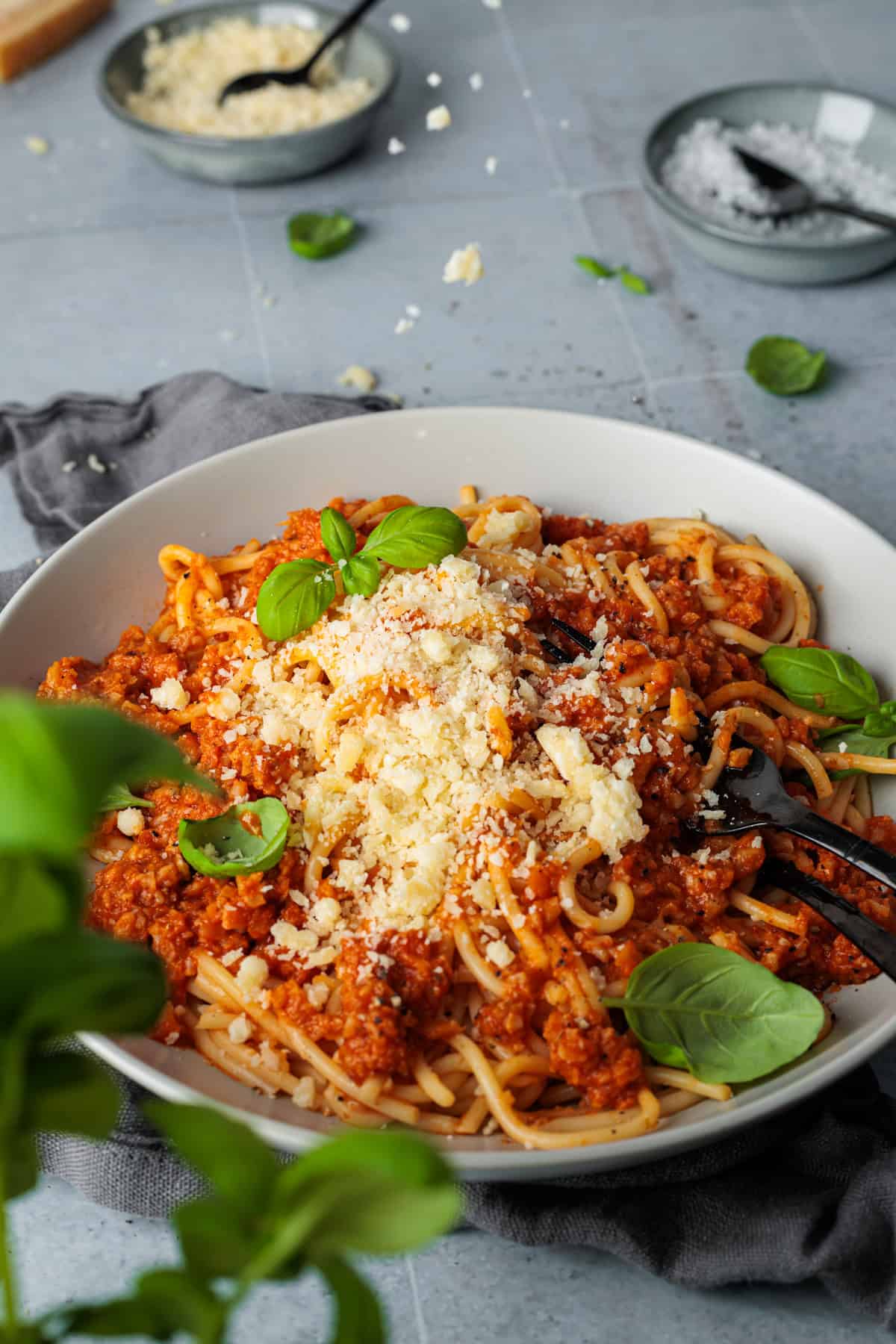 Nahaufnahme einer vegetarischen Blumenkohl-Champignon-Bolognese mit Spaghetti. Dieses gesunde Feierabend-Rezept aus dem Thermomix® ist kalorienarm und perfekt für eine schnelle, fleischlose Ernährung. Das Bild zeigt die herzhafte Textur der Gemüsesoße, garniert mit frischem Basilikum und Parmesan.